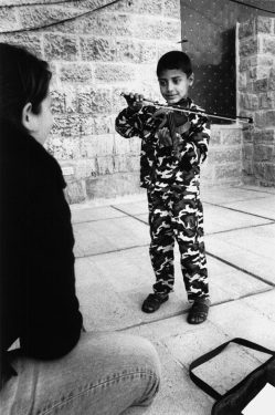 Der 8-jährige Ahmed in Tarnkleidung, Geige spielend