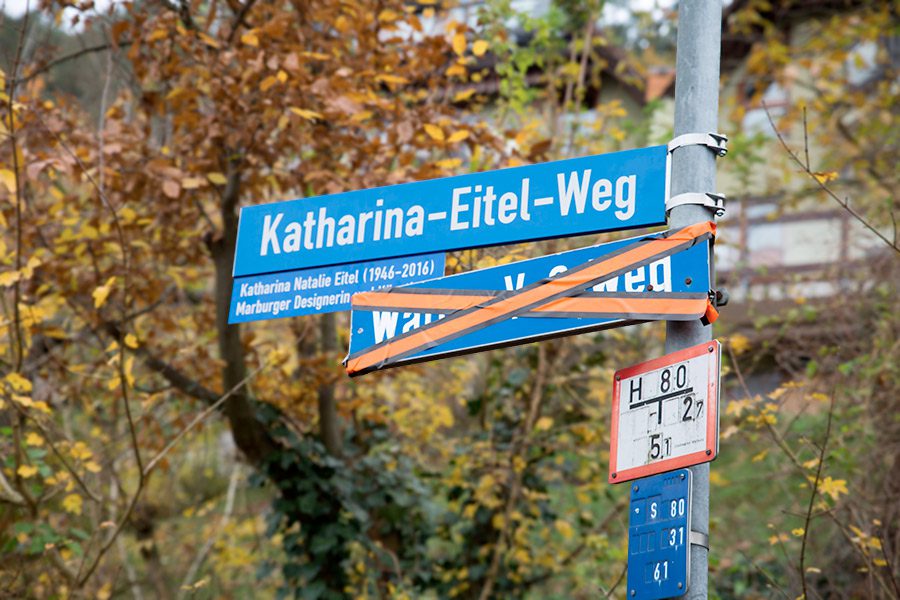 Das neue Straßenschildes im Katharina-Eitel-Weg, darunter das alte Schild mit orangenem Band kreuzweise abgeklebt (Foto: Stadt Marburg, Patricia Grähling)